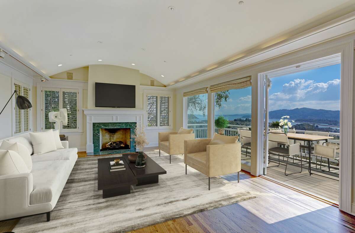 The living room features a fireplace and glass walls that open to deck overlooking the Bay.