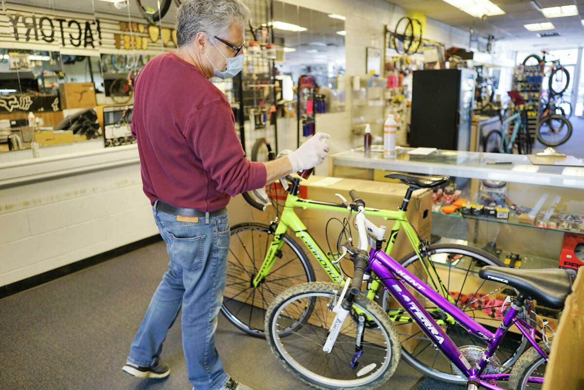 Jeff Pepper, owner of CK Cycles, sprays a disinfectant on bikes brought in for repairs at his shop on Tuesday, May 5, 2020, in Colonie, N.Y. Customers are met in the parking lot by employees of the bike shop. (Paul Buckowski/Times Union)