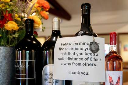 A sign asks customers to properly social distance while they dine at Fume Bistro in Napa, Calif. Tuesday, May 5, 2020. A handful of businesses in Napa have made the decision to begin reopening their dining rooms at a limited scale ahead of shelter-in-place orders.