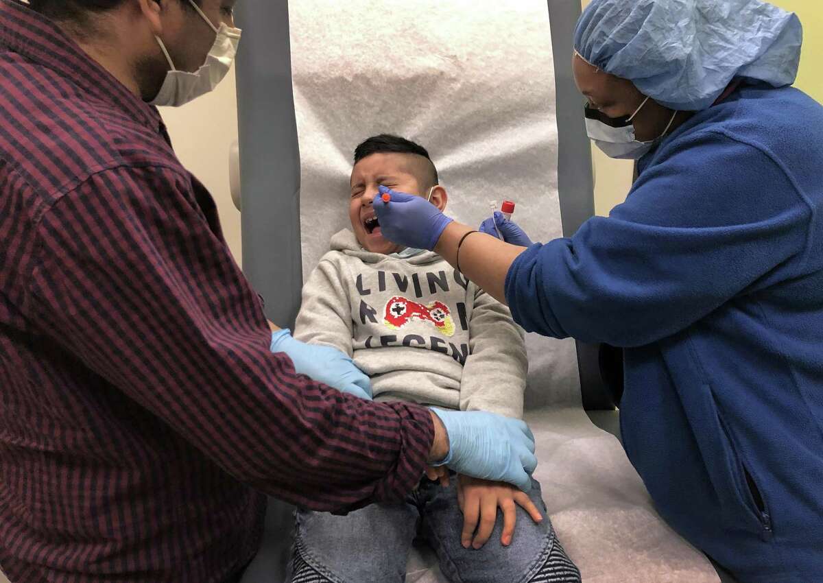 Guatemalan immigrant Junior, 7, receives a COVID-19 swab test from a nurse as his father Marvin holds him down at a clinic on May 5, 2020 in Stamford, Connecticut. Junior and Marvin were being re-tested to see if they are now are negative, a month after getting sick from coronavirus.