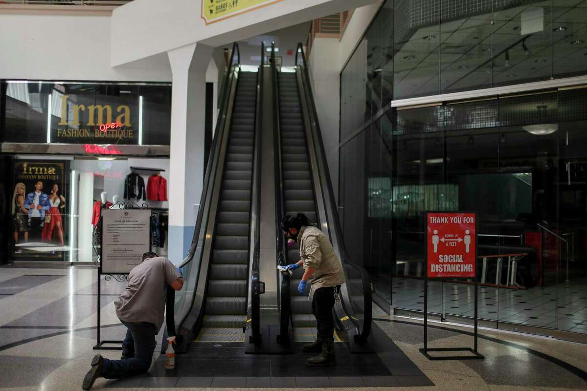 Workers clean an escalator at PlazAmericas mall on Friday. The local economy could lose as many as 83,200 jobs due to a recession caused by the coronavirus.
