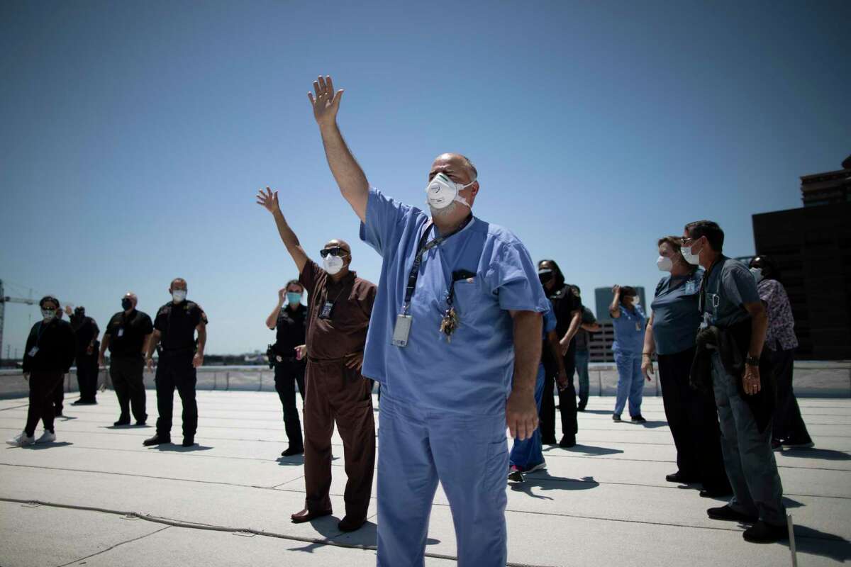 Medical staff and deputy from the Harris County Sheriff's Office observe the United States Navy's Blue Angels as they fly by from the rooftop of the Harris County Jail on Wednesday, May 6, 2020, in Houston.