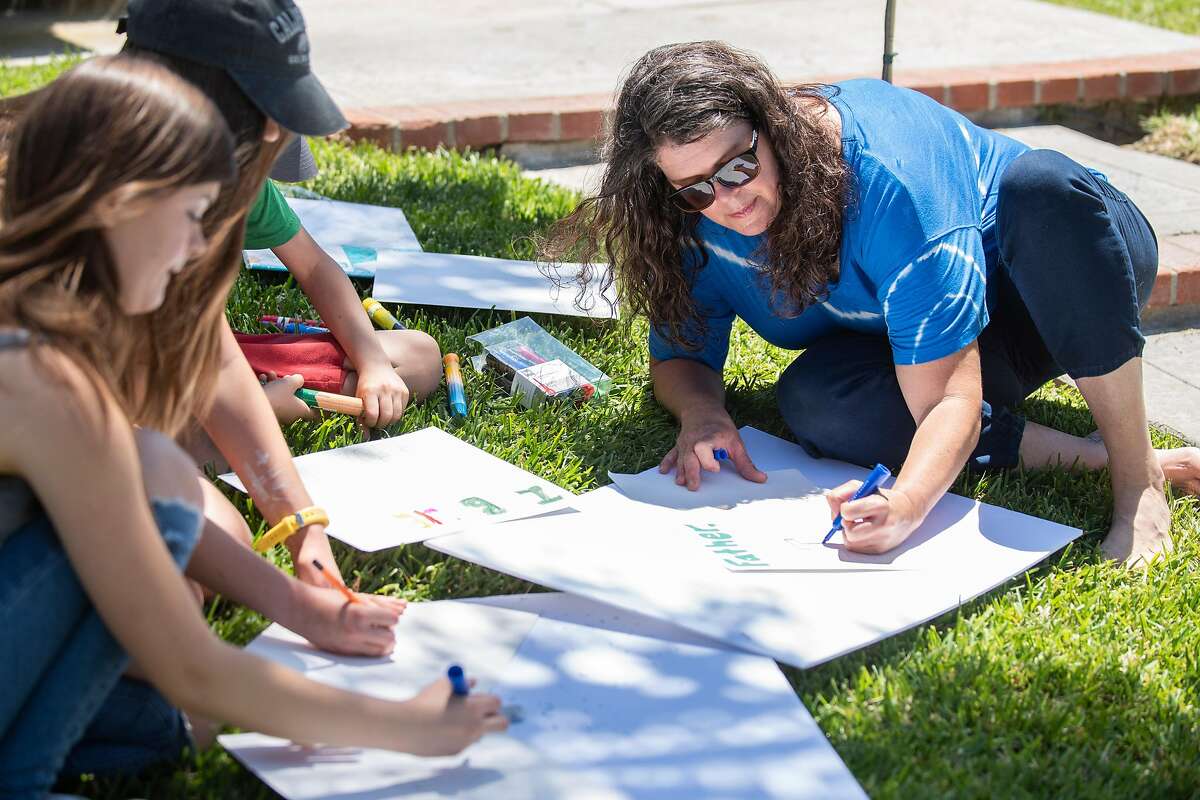 Stefanie Duncan Fetzer, left, and her children makes signs for an upcoming "Open California" rally at the California State Capital in Sacramento, on Wednesday, May 6, 2020 in their front yard in San Clemente, Calif.