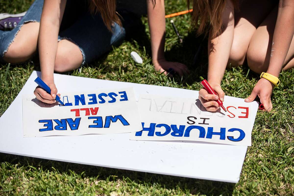 Sisters Hallie Fetzer, 15, and Sidney Fetzer, 15, make signs for an upcoming "Open California" rally at the California State Capital in Sacramento, on Wednesday, May 6, 2020 in their front yard in San Clemente, Calif.