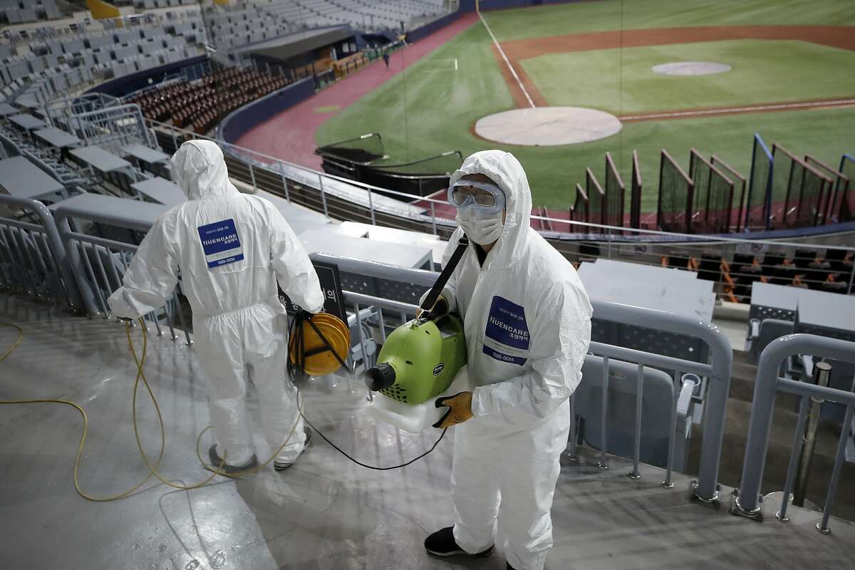 Workers wearing protective gears disinfect as a precaution against the new coronavirus at Gocheok Sky Dome in Seoul, South Korea, Tuesday, March 17, 2020. The Korea Baseball Organization has postponed the start of new season to prevent the spread of the new coronavirus. For most people, the new coronavirus causes only mild or moderate symptoms. For some it can cause more severe illness. (AP Photo/Lee Jin-man)
