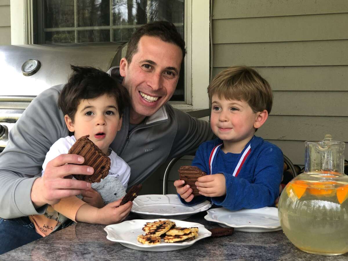 Michael Fensterstock of Wilton and sons Blaire, 2, and Parker, 3, enjoy chocolate arepas, one of three flavors of arepas being sold by Fensterstock’s door-to-door business alldaysnacks.com.