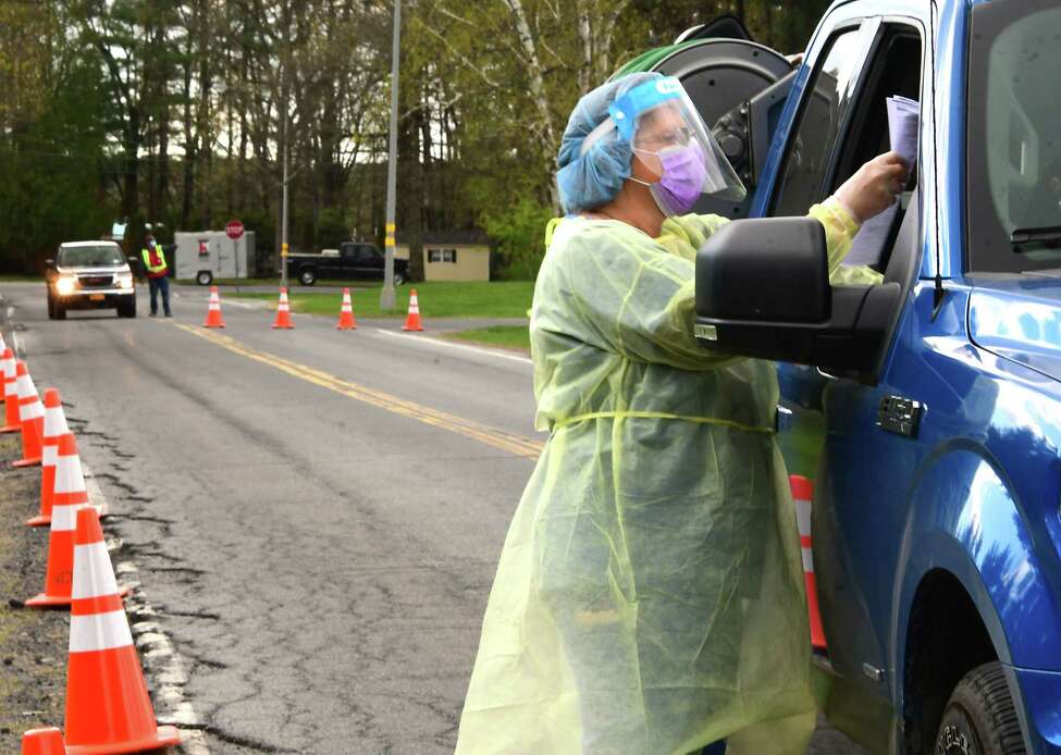 A healthcare worker gives a patient paperwork at a COVID-19 testing site behind Warren County Municipal Center on Thursday, May 7, 2020 in Queensbury, N.Y. (Lori Van Buren/Times Union)