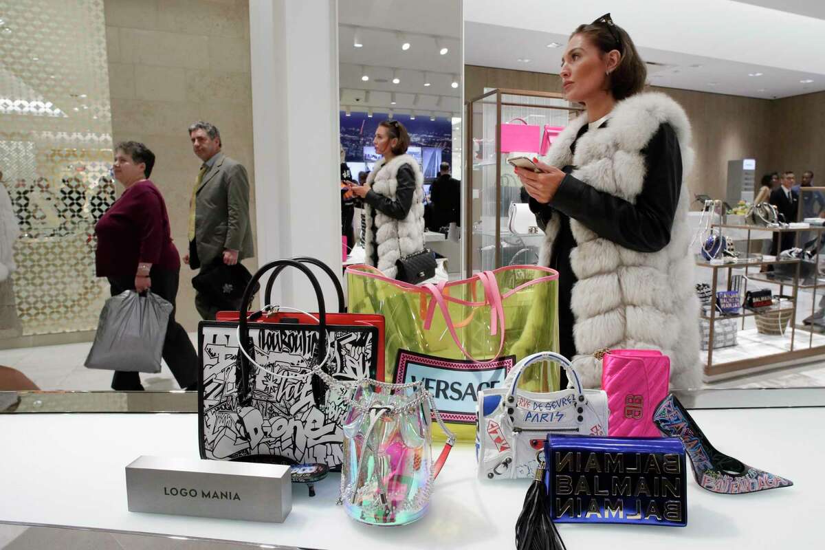 FILE- In this March 14, 2019, file photo a woman shops at Neiman Marcus during the opening night of The Shops & Restaurants at Hudson Yards in New York. Luxury department stores like Neiman Marcus and Saks Fifth Avenue once ruled among the affluent set. Now, they’re fighting a tough battle to lure younger shoppers faced with a lot more shopping choices, including second-hand retailers and fashion rental companies. (AP Photo/Mark Lennihan, File)