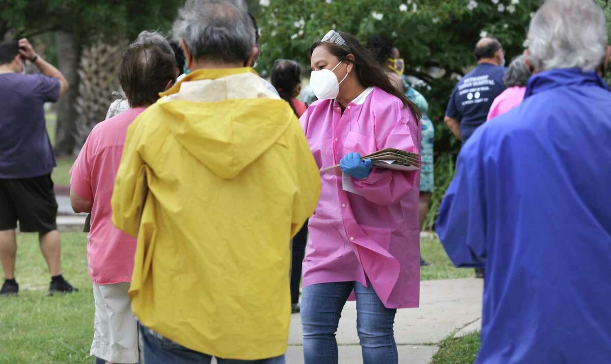 Yvonne Ramirez of the San Antonio Metropolitan Health District collects information forms from individuals waiting for COVID-19 testing at Woodlawn Lake, on Thursday, May 7, 2020.
