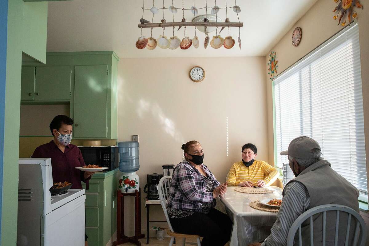From left: Francisca Gonzalez, her sister Juana Gonzalez, father Carmelo Gonzalez Puga and family friend Paola Pe�a prepare for dinner on Thursday, May 7, 2020, in San Jose, Calif. Carmelo Gonzalez Puga said he tested positive for the coronavirus in mid April and has since recovered from COVID-19.
