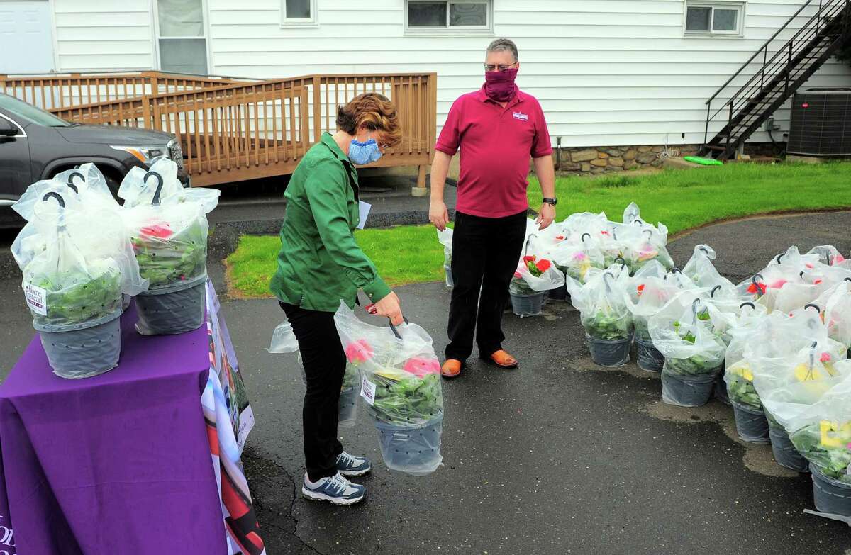 Home Instead Franchise Owner Coleman Gately looks on as caregiver Tisha Iannacone grabs a flower basket for Mother's Day at Home Instead's offices in Norwalk, Conn., on Saturday May 8, 2020. The flowers, donated through Lowe's, were delivered staff caregivers and the mothers and grandmothers they work with who may feel socially isolated on Mother's Day because of the coronavirus.