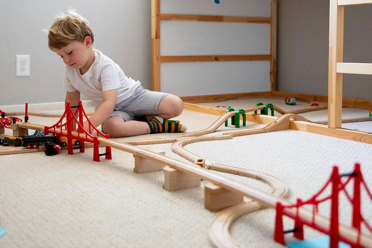 Liam Havenar-Daughton, 3, plays with a toy train set in the bedroom of his home in El Sobrante, Calif. Thursday, May 7, 2020. Despite federal and state funding, hundreds of childcare facilities may shut down due to the Coronavirus pandemic, leaving parents with nowhere to leave their kids when the economy reopens and they want to return to work. The Havenar-Daughtons pay $1,900 a month for childcare they can't use during the shelter in place period, fearing that otherwise they might lose the preschool and nanny who watches their children.