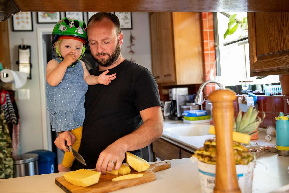 Brendan Havenar-Daughton cuts pineapple for him and his daughter during lunchtime at their home in El Sobrante, Calif. Thursday, May 7, 2020. Despite federal and state funding, hundreds of childcare facilities may shut down due to the Coronavirus pandemic, leaving parents with nowhere to leave their kids when the economy reopens and they want to return to work. The Havenar-Daughtons pay $1,900 a month for childcare they can't use during the shelter in place period, fearing that otherwise they might lose the preschool and nanny who watches their children.