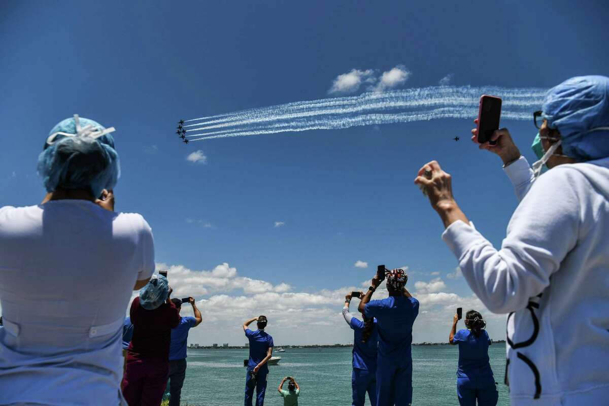 Health care workers gather by the bay to watch the U.S. Navy Blue Angels and U.S. Air Force Thunderbirds fly over Mount Sinai Medical Center in Miami on Friday. The Thunderbirds will fly over San Antonio and Austin on Tuesday. (Photo by CHANDAN KHANNA / AFP) (Photo by CHANDAN KHANNA/AFP via Getty Images)