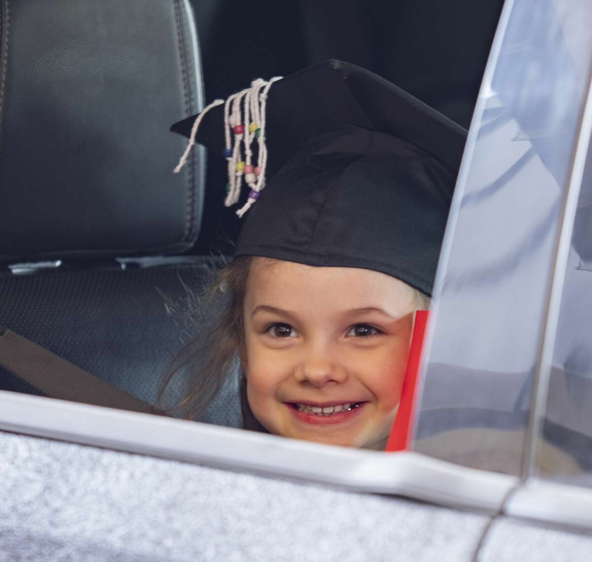 Midland College Pre-K Academy graduate Makynlee Lavender smiles for a picture in her graduation cap 05/08/2020 as parents drive through the parking lot to receive their diploma as the first class to graduate from the Academy. Tim Fischer/Reporter-Telegram