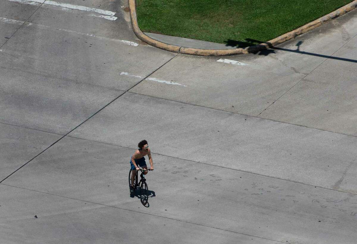 A bicyclist pedals through the intersection of Cambridge and South MacGregor on May 6, 2020, in Houston.