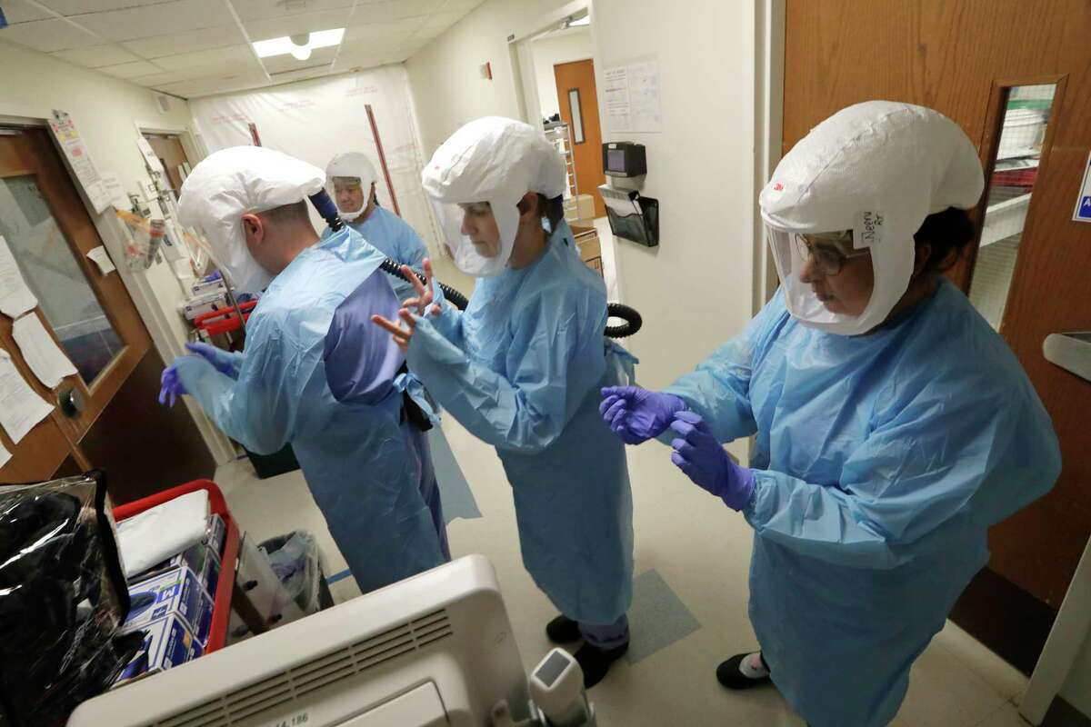 A team of medical workers wearing respirators and protective gear ready to enter the room of a patient in the COVID-19 Intensive Care Unit at Harborview Medical Center, Friday, May 8, 2020, in Seattle. Data from COVID-19 projection models show that the rate of infection is increasing in Washington state, Gov. Jay Inslee said Friday, as he urged people to follow his measured approach to slowly reopening the state from his stay-at-home restrictions.