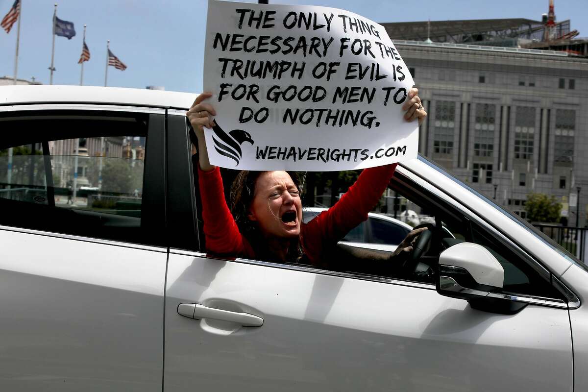 A woman protests from her vehicle during a rally in front of City Hall calling for Gov. Newsom to immediately reopen California completely in San Francisco, Calif., on Saturday, May 9, 2020. Protesters argued they've been stripped of their rights.