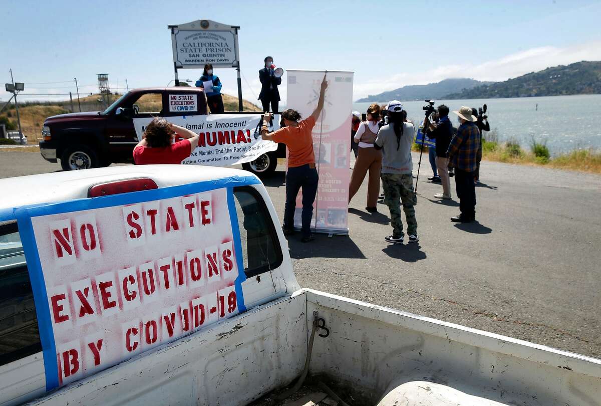 About a dozen protesters maintain social distance at the west gate of San Quentin State Prison while a caravan of demonstrators in cars drives back and forth to demand more protection against the COVID-19 coronavirus for prisoners in Larkspur, Calif. on Saturday, May 9, 2020.