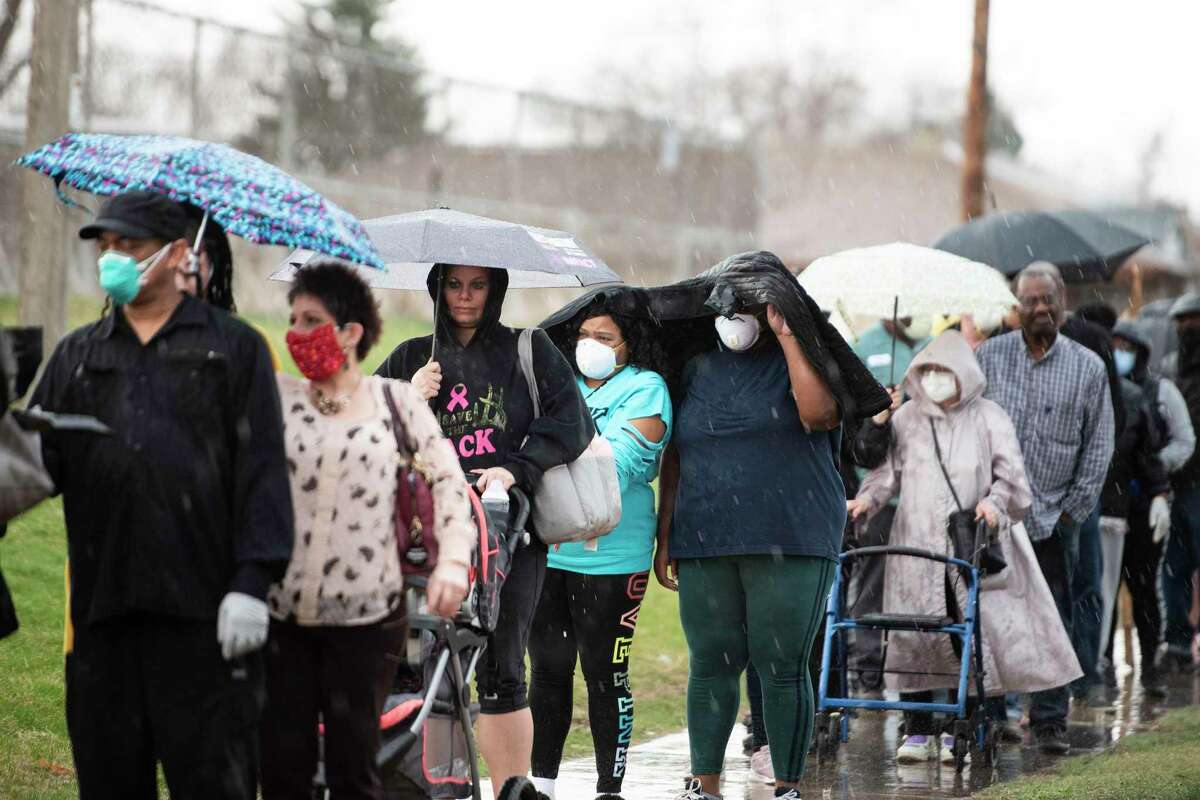 Rain falls on people waiting in line to vote at Milwaukee Marshall High School in Milwaukee, on April 7, 2020, during primaries that took place during the novel coronavirus pandemic. A Rice University survey looked at Harris County voters’ and poll workers’ willingness to vote during a pandemic.