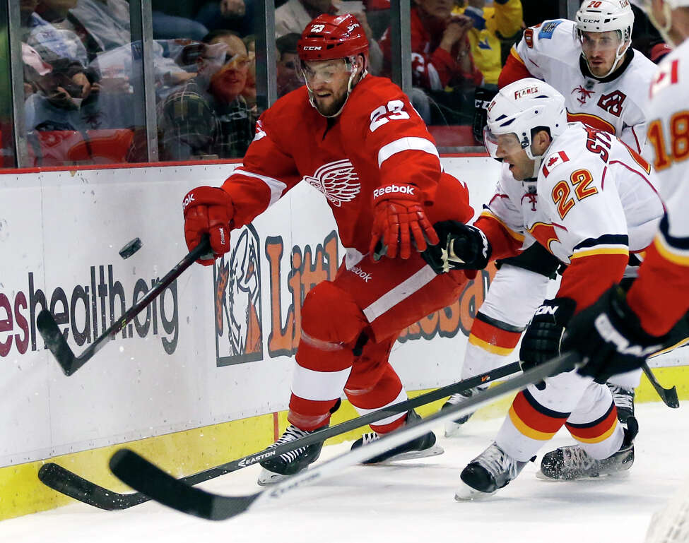Detroit Red Wings' Brian Lashoff (23) and Calgary Flames' Lee Stempniak (22) chase the loose puck during the first period of an NHL hockey game, Thursday, Dec. 19, 2013, in Detroit. (AP Photo/Duane Burleson) ORG XMIT: DTA103
