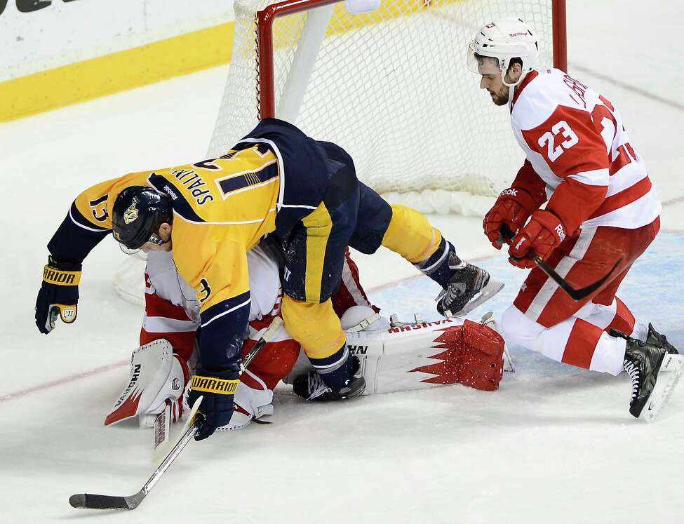 Nashville Predators forward Nick Spaling (13) falls over Detroit Red Wings goalie Jimmy Howard after stopping a shot by Spaling while being defended by Red Wings defenseman Brian Lashoff (23) in the second period of an NHL hockey game on Monday, Dec. 30, 2013, in Nashville, Tenn. (AP Photo/Mark Zaleski) ORG XMIT: TNMZ108