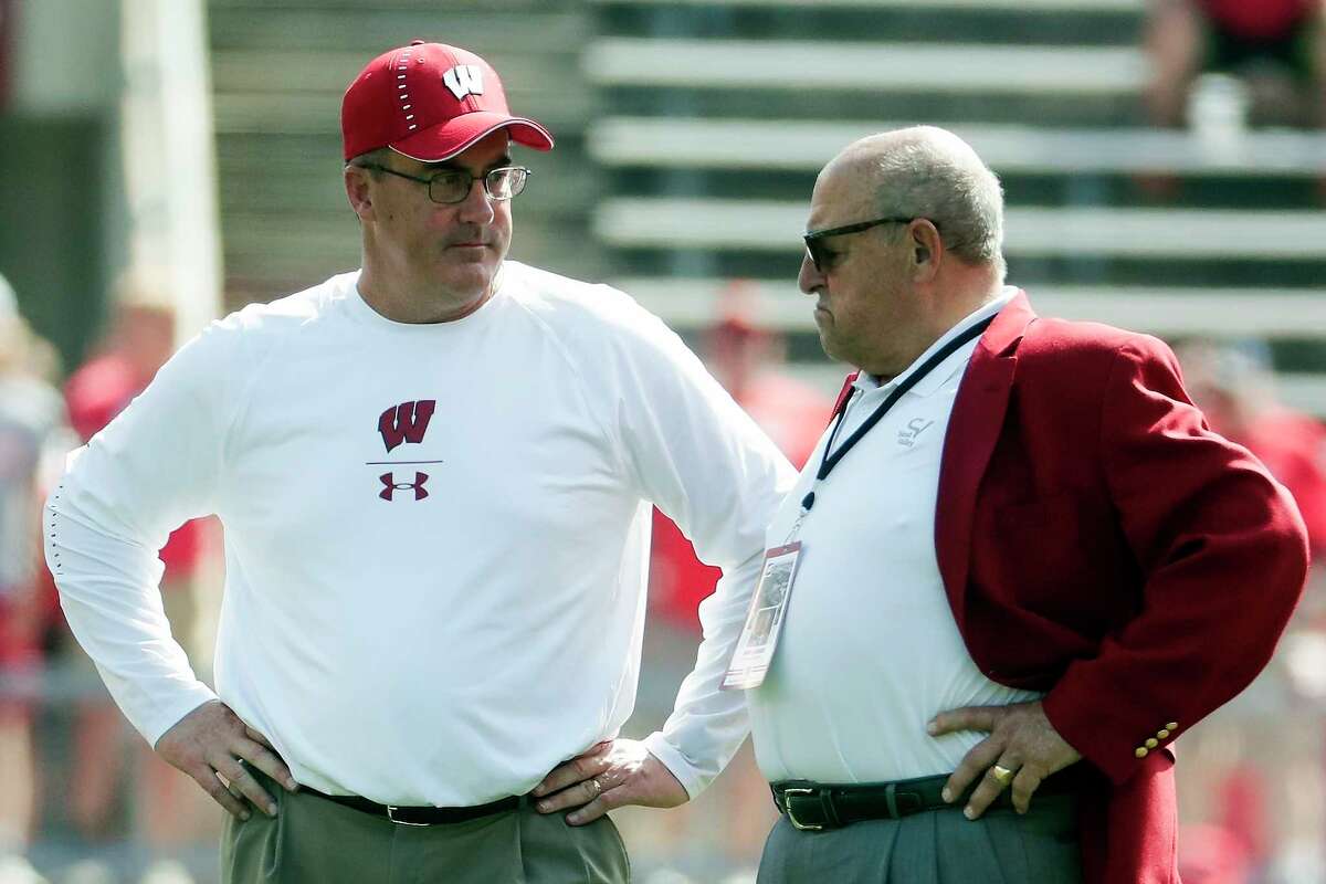 FILE - In this Sept. 15, 2018, file photo, Wisconsin head coach Paul Chryst, left, talks to athletic director Barry Alvarez before an NCAA college football game against BYU in Madison, Wis. Wisconsin announced Saturday, May 9, 2020, it is asking 25 of its highest-earning employees to volunteer for a 15% pay cut over the next six months. That group includes athletic director Barry Alvarez, football coach Paul Chryst and men's basketball coach Greg Gard. There won't be any reduction of work hours. (AP Photo/Morry Gash, File)