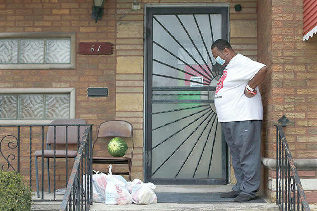 Anthony Travis, who has recovered from COVID-19 and lives with his sister and an adult daughter, looks at a surprise anonymous delivery of groceries on the porch of his Riverdale home.