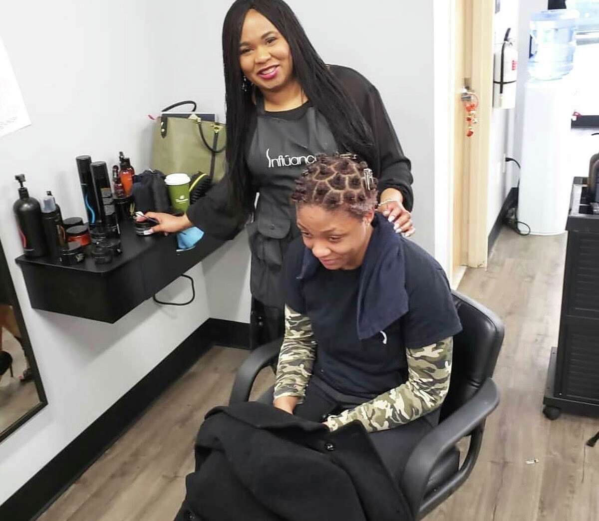 African American salon owners say they can’t open without being allowed to offer blow drying — it’s part of the service for black women’s hair.  Shown is Tasheba Taylor of Indigo Hair Innovations in West Hartford and Newington with a client.
