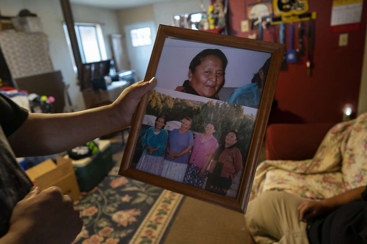 Eugene Dinehdeal holds photos of family members, including Eva Dinehdeal at top, at the Dinehdeal family compound in Tuba City, Ariz., on the Navajo reservation on April 20, 2020. Eva Dinehdeal died of COVID-19 on April, 11, 2020. (AP Photo/Carolyn Kaster)