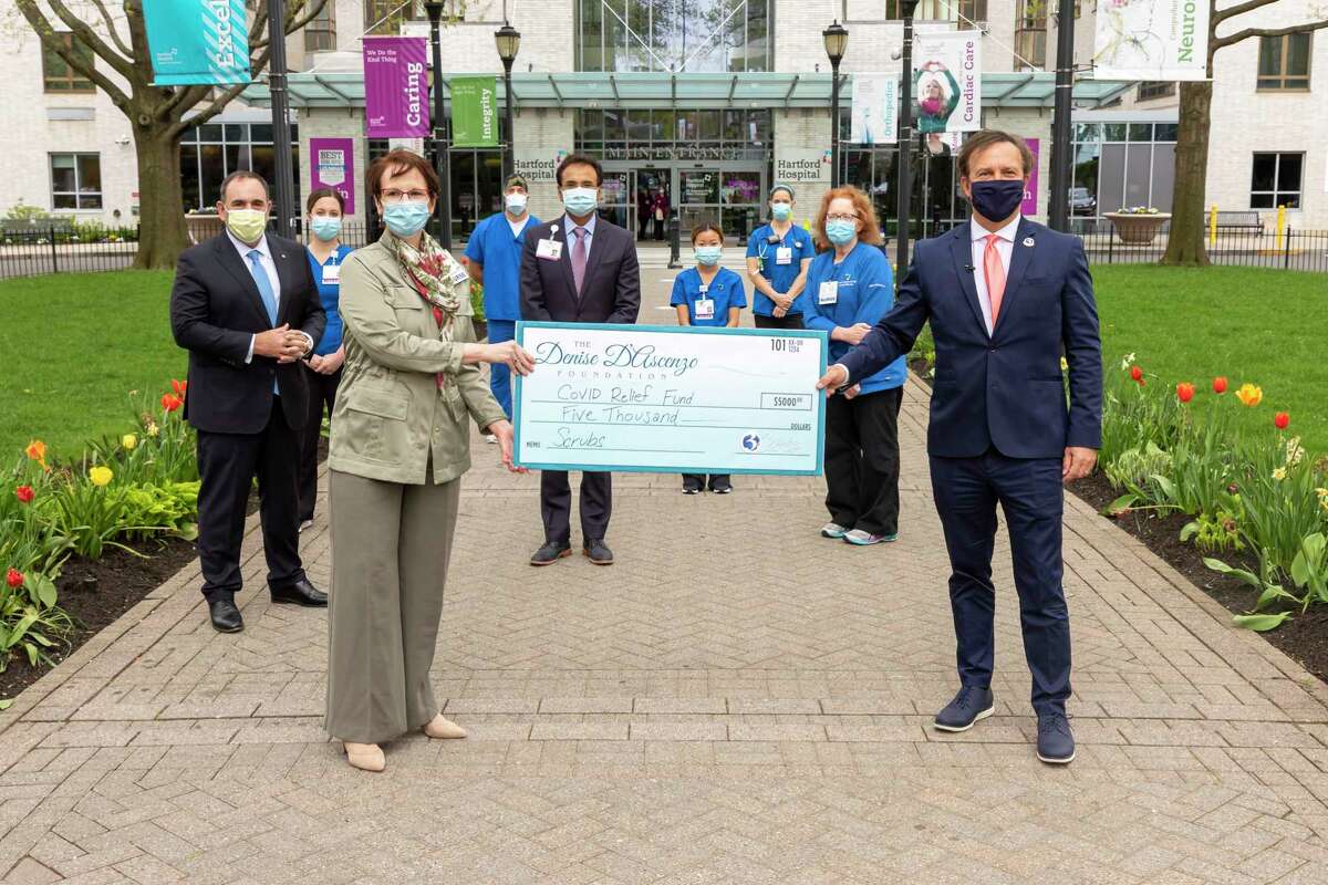 The Denise D’Ascenzo Foundation presented a check for $5,000 outside Hartford Hospital on Monday, May 4, 2020, to support The Hartford Hospital COVID-19 Fund. Pictured, from left: Jeffrey A. Flaks, president and CEO, Hartford HealthCare; Cheryl Ficara, regional vice president for patient care services, Hartford Hospital; Bimal Patel, president - Hartford Hospital & Hartford region, senior vice president, Hartford HealthCare; and WFSB TV anchor Dennis House of The Denise D’Ascenzo Foundation, standing among Hartford Hospital front-line nurses and emergency medicine professionals.