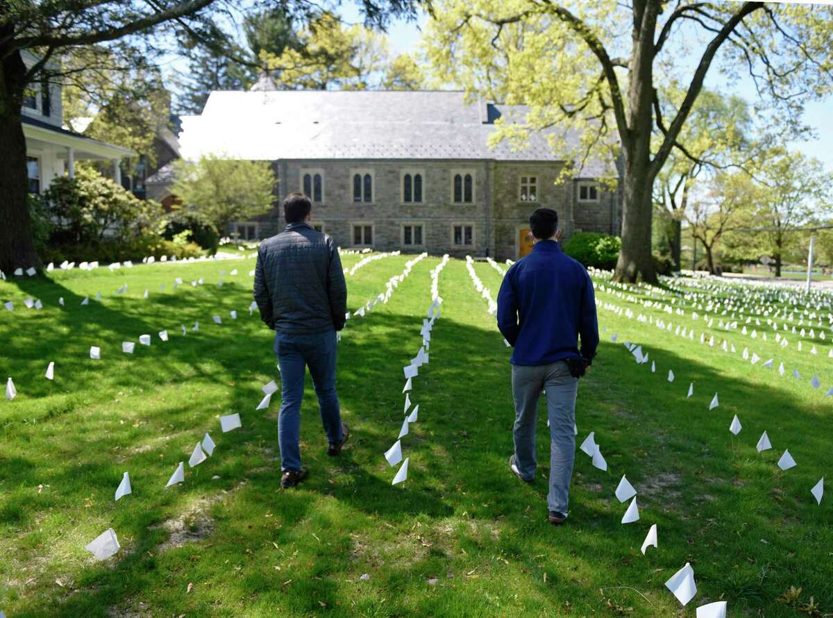 U.S. Rep. Jim Himes, D-Conn., left, and the Rev. Patrick Collins look upon flags placed in memory of lives lost to coronavirus at First Congregational Church of Greenwich in Old Greenwich, Conn. Tuesday, May 12, 2020. The Rev. Collins placed flags in memory of 41 lives lost to coronavirus on Tuesday, bringing the total to more than 3,000.