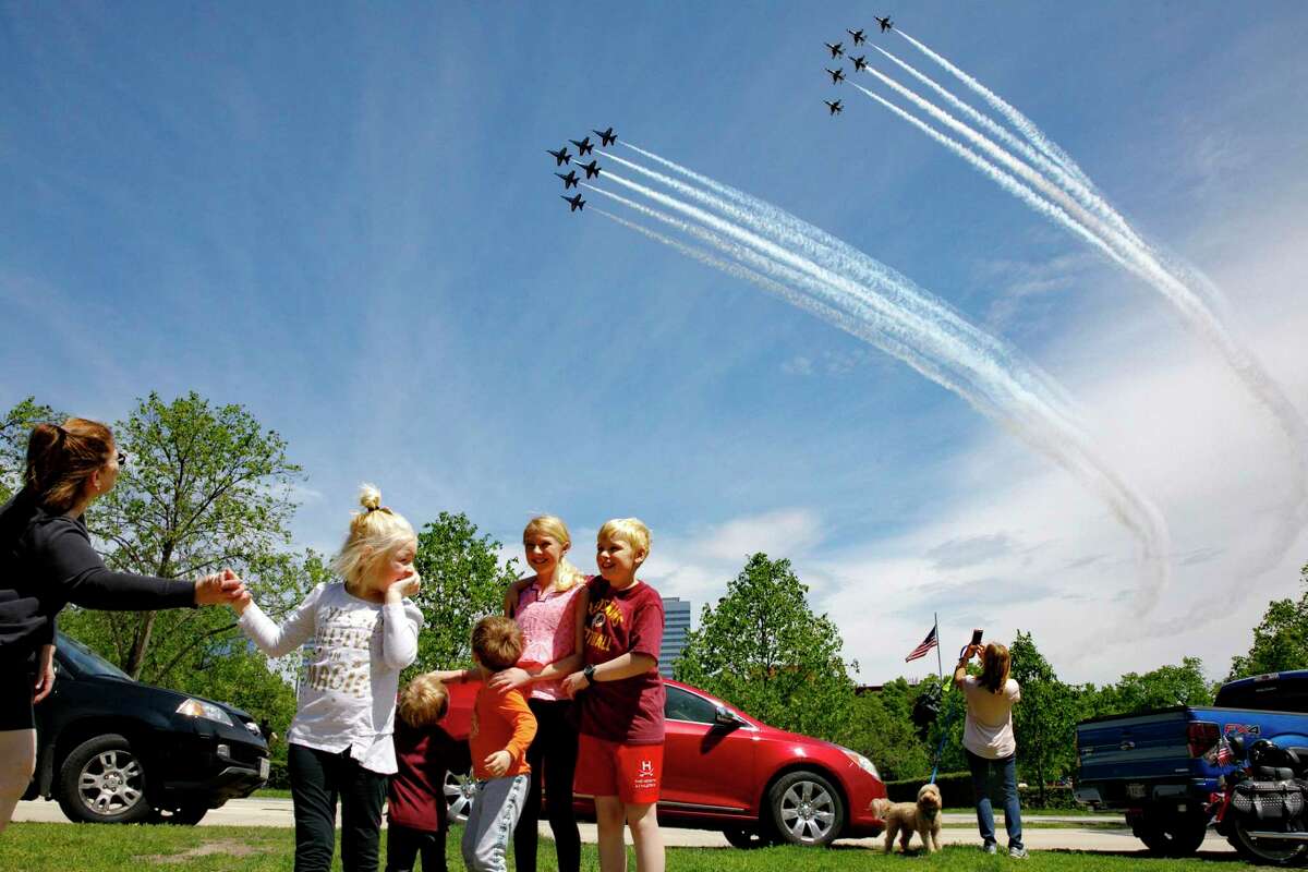 The Ferry family, from Chantilly, Va., who were in the middle of taking a family photograph, are surprised by a second fly over by the Blue Angels and Thunderbirds, in a "salute to frontline COVID-19 responders," as seen near the U.S. Marine Corps War Memorial that depicts a flag raising over Iwo Jima, in Arlington, Va., Saturday, May 2, 2020. (AP Photo/Jacquelyn Martin)