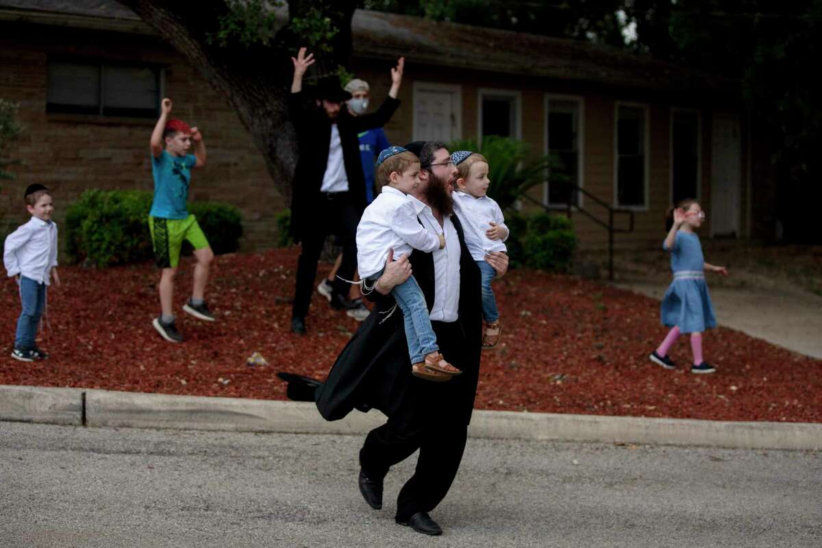 Rabbi Levi Grossbaum dances with his sons Dovber, 4, and Akiva, 3, during Tuesday’s drive-thru Lag BaOmer celebration reimagined for social distancing at the Chabad Center for Jewish Life & Learning in San Antonio.