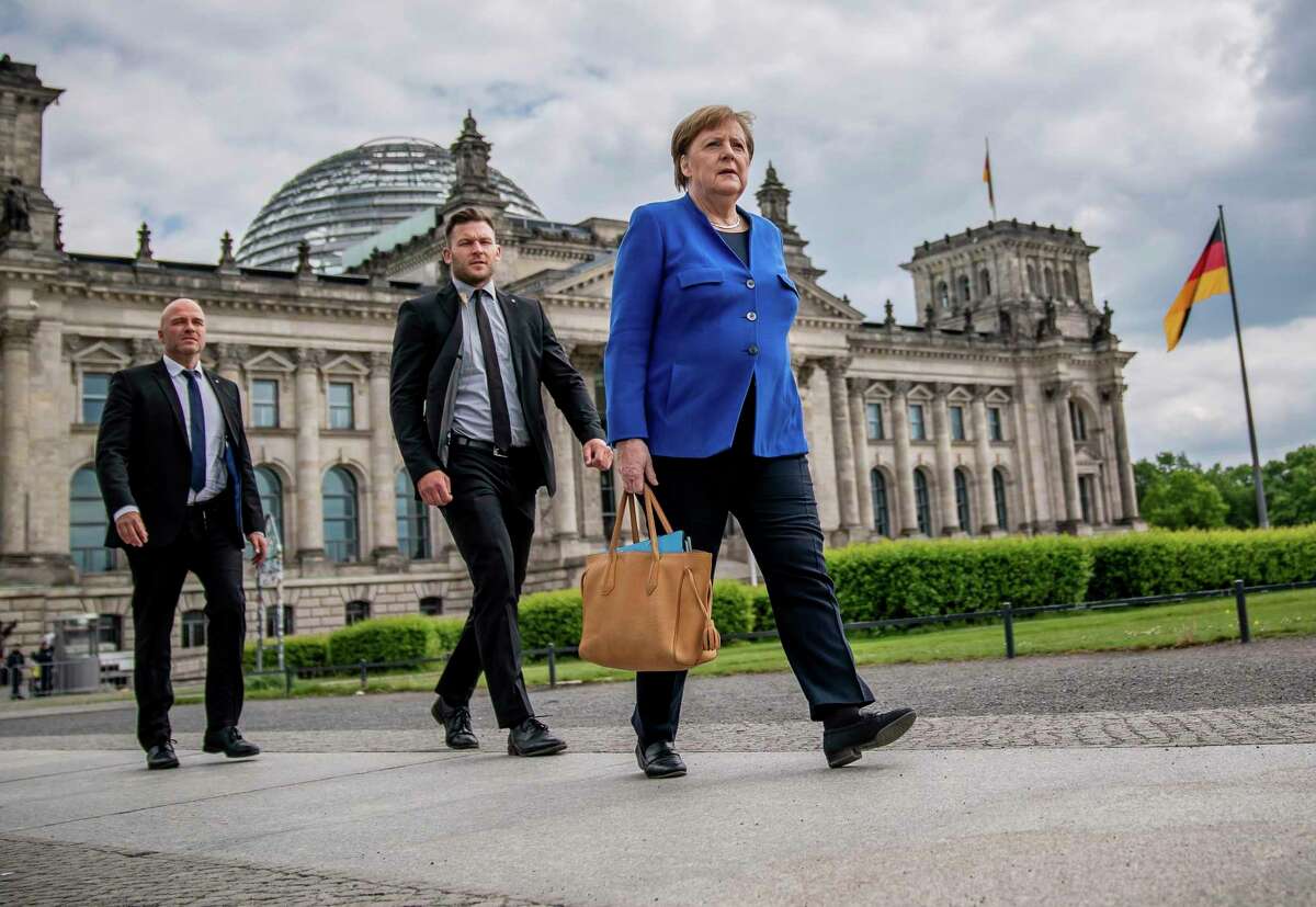 Chancellor Angela Merkel walks to the Chancellery on foot, accompanied by her bodyguards, after the government questioning in the Bundestag in Berlin, Germany, Wednesday, May 13.