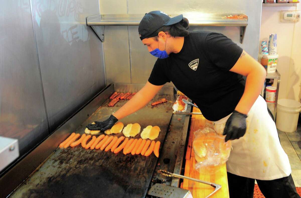 An employee at Super Duper Weenie cooks hot dogs at the restaurant in Fairfield, Conn., on Wednesday May 13, 2020. The restaurant is planning to move some picnic tables from an inner courtyard into its parking lot to provide outdoor seating for the resumption of dine-in eating on May 20.