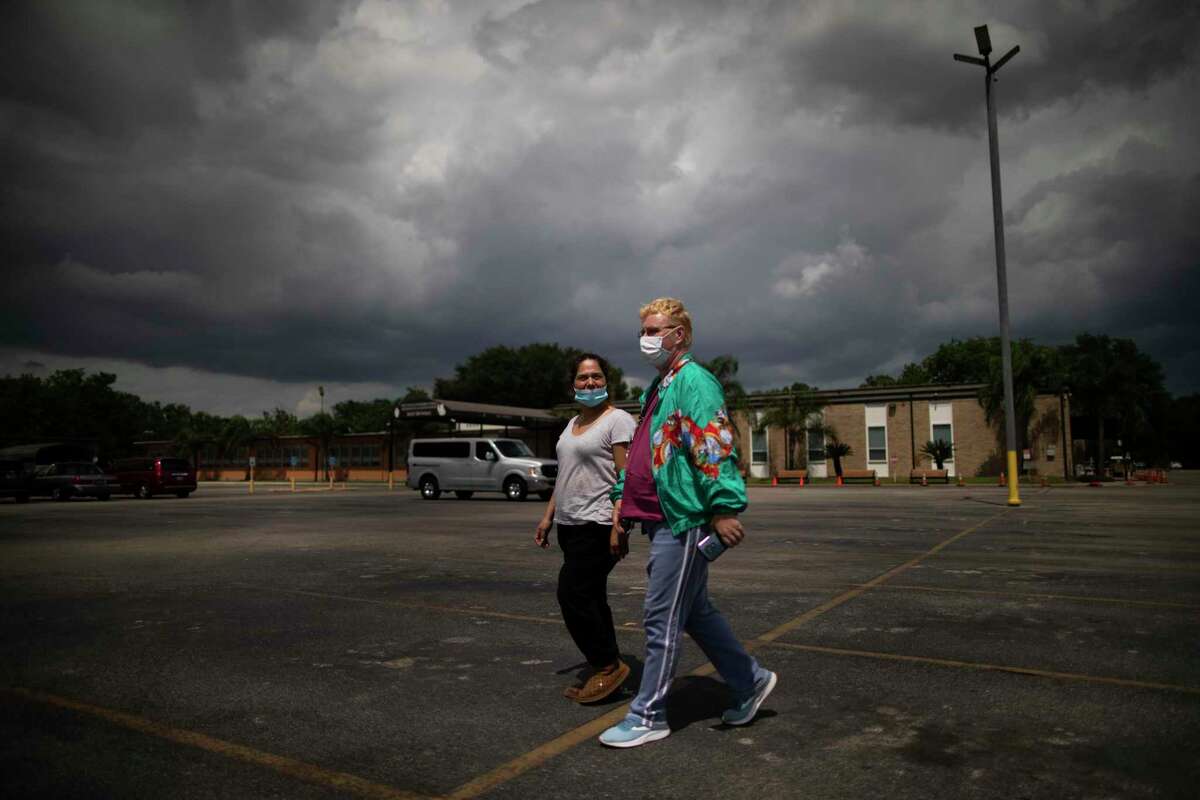 Jacquelyn Guyton, 52, and her friend Debbie Saldana, 43, walk to in the parking area of the St. Charles Borromeo Catholic Church to pick up food assistance.