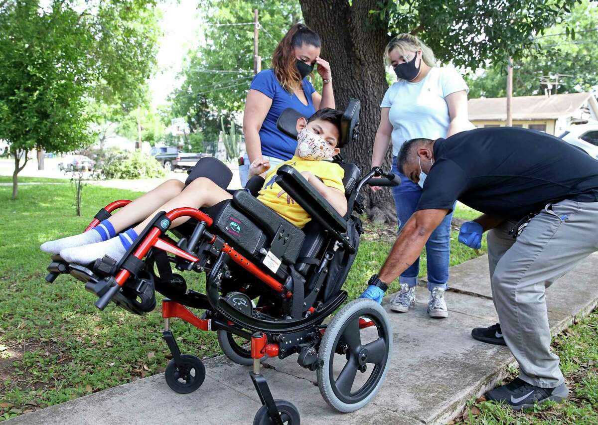 Freddie Zapata of Project Mend adjusts 7-year-old Jayden Arispe’s new wheelchair as Jayden, his mom Juanita Cortez, left, and Cortez’s daughter Gia watch May 8, 2020. Zapata delivered the new equipment and helped Arispe get settled in.
