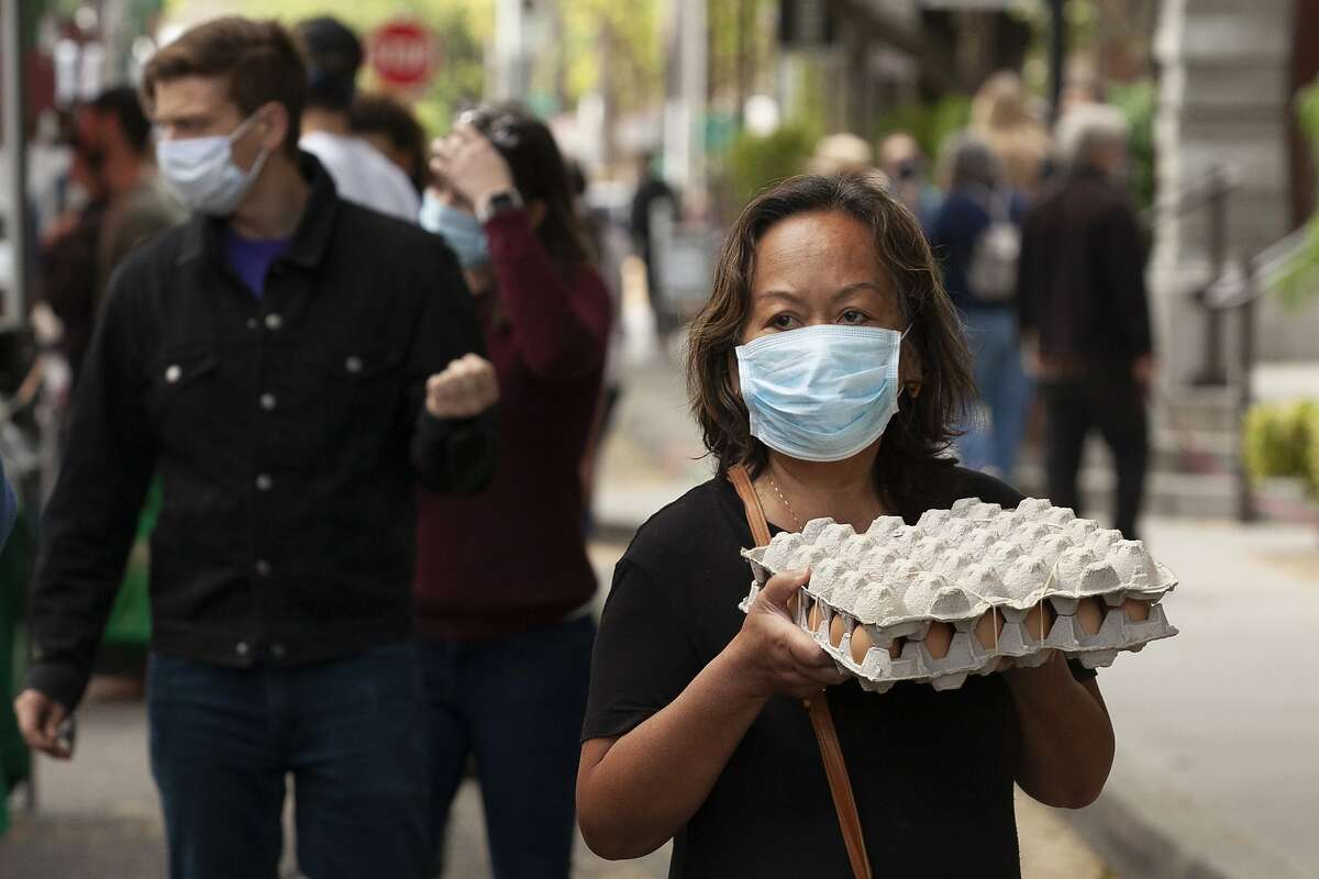 Rumony Noah carries a carton of eggs she purchased at the Midtown Farmers Market in Sacramento, Calif., Saturday, April 18, 2020. Noah, like many others at the market, wore a face mask and practiced social distancing as she did her shopping, during the coronavirus outbreak. (AP Photo/Rich Pedroncelli)