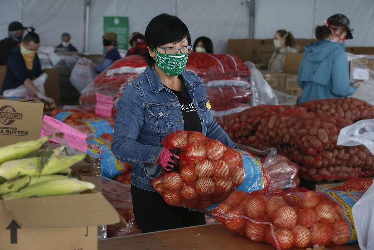 Jen Woo, a librarian from the West Portal branch, sorts onions on her volunteer shift at the SF-Marin Food Bank during the coronavirus pandemic in San Francisco, Calif. on Wednesday, May 13, 2020.