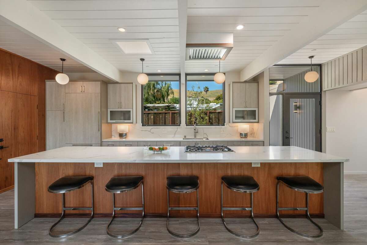 Just as in the original home, the kitchen is right off the entry, but now it is opened to the rest of the entertaining space and centers around a huge island with gas range.
