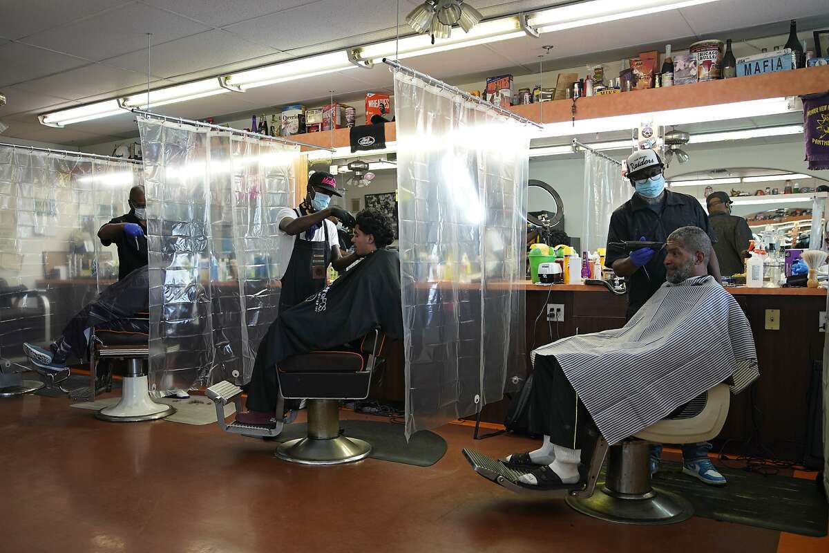 Plastic sheets separate customers at A Cut Above the Rest barber shop, Saturday, May 9, 2020, in Las Vegas. Saturday was the first day restaurants, salons and other nonessential businesses were allowed to start reopening after restrictions were imposed seven weeks earlier to help stop the spread of the new coronavirus. (AP Photo/John Locher)