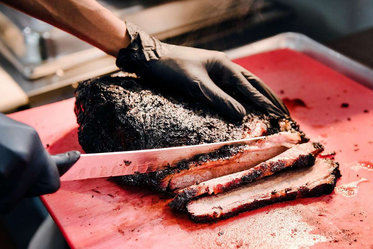 Cook Bobby Garcia slices brisket in the kitchen at Smokin Woods BBQ in Oakland, Calif, on Thursday, May 14, 2020.