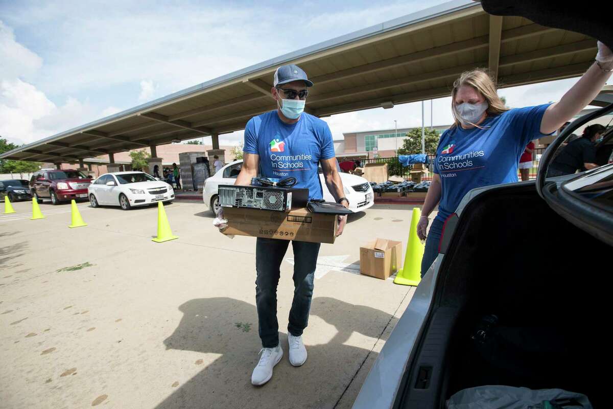 Roy Reyes, community support specialist with Communities In Schools, and Lisa Descant load a computer into the back of a vehicle while helping distribute desktop computers to the students at Ridgecrest Elementary School on Friday, May 15, 2020 in Houston. Communities In Schools of Houston distributed 275 computers to help the Ridgecrest students with remote learning amid the coronavirus pandemic and school closings. CIS is teaming up with Comp-U-Dopt to distribute 5,000 computers across the city needed for virtual school work.