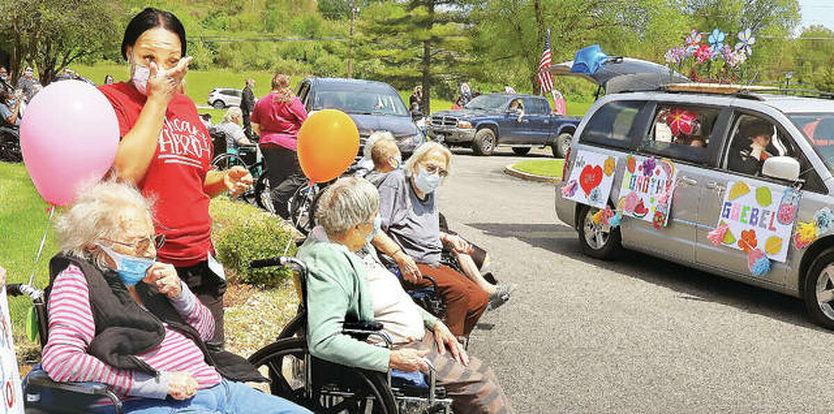 A staff member at Riverside Rehabilitation and Healthcare Center on Humbert Road in Alton, left, wipes away a tear May 1 during a drive-through parade at the facility. On Saturday it was announced the facility was the location of a coronavirus cluster with 15 cases and two deaths.