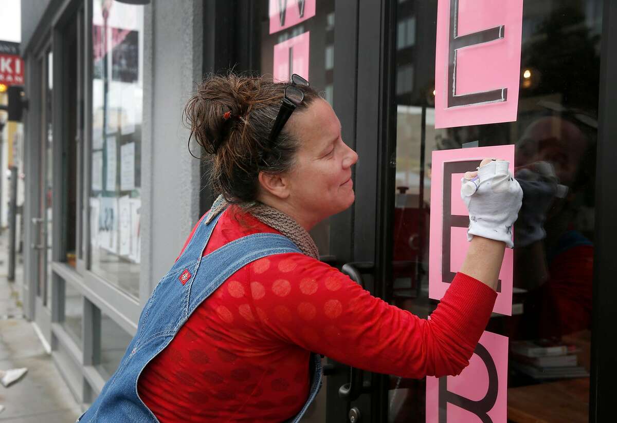 Sign painter Libby Staub traces letters for a sign at Altalena Vinoteca in San Francisco, Calif. on Thursday, May 14, 2020. Staub is angry that Veritas, manager of more than 250 apartment buildings in the city, including hers, received 3.6 million in PPP relief funds form the federal government but she has yet to receive hers.
