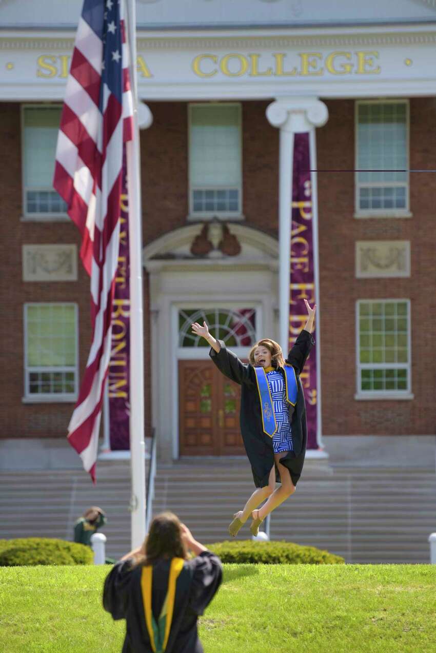 Siena College graduate, Kathleen O'Toole of Colonie, gets her photo taken by fellow graduate Cate Lawyer of Albany on the college's campus on Sunday, May 17, 2020, in Loudonville, N.Y. The two women showed up at the campus to take photos on what was the school's graduation day. The two borrowed graduation gowns from Lawyer's family members who are Siena alumni. Siena College officials also held a ceremony to honor the class of 2020, the event was streamed live on Siena's Facebook page. College officials announced that they are tentatively planning for an actual graduation ceremony for the class of 2020 on August 15th. (Paul Buckowski/Times Union)