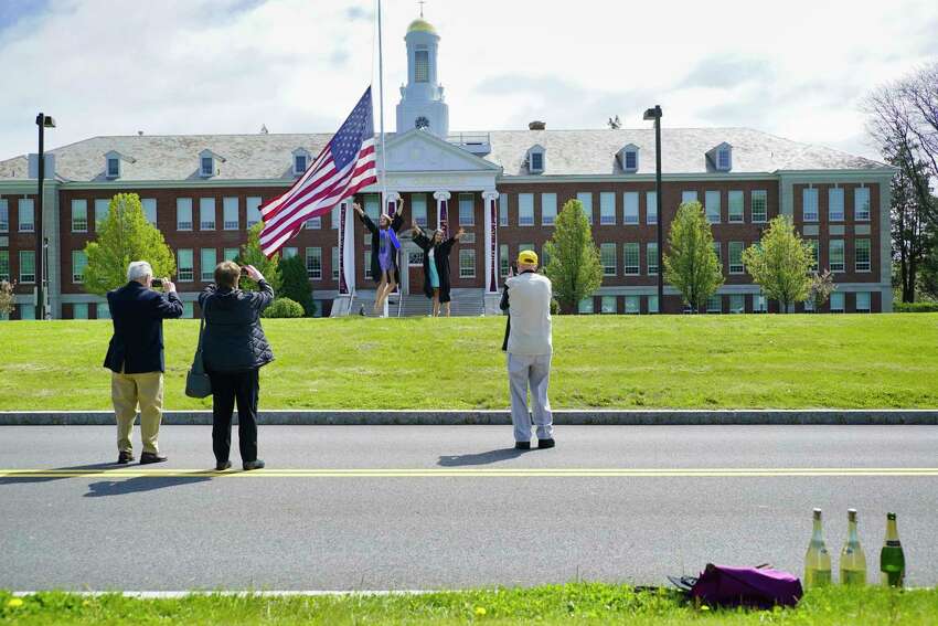 Siena College graduates, Kathleen O'Toole, left, of Colonie, and Cate Lawyer of Albany get their photos taken by family members on the college's campus on Sunday, May 17, 2020, in Loudonville, N.Y. The two women showed up at the campus to take photos on what was the school's graduation day. The two borrowed graduation gowns from Lawyer's family members who are Siena alumni. Siena College officials also held a ceremony to honor the class of 2020, the event was streamed live on Siena's Facebook page. College officials announced that they are tentatively planning for an actual graduation ceremony for the class of 2020 on August 15th. (Paul Buckowski/Times Union)
