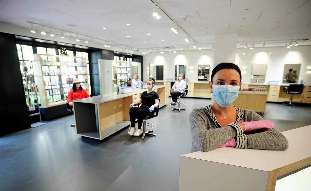 Manager Maria Farago wears a protective mask as employees sit at reconfigure work stations at Hopscotch Salon in Greenwich Connecticut on May 15, 2020. The salon which is located inside the Greenwich Hyatt Regency hotel, is preparing to re-open after thoroughly de-sanitizing and re configuring the salon to meet the COVID-19 safety requirements set by the state. Barriers have been installed and every other work station closed to protect clients and prevent the spread of the coronavirus.