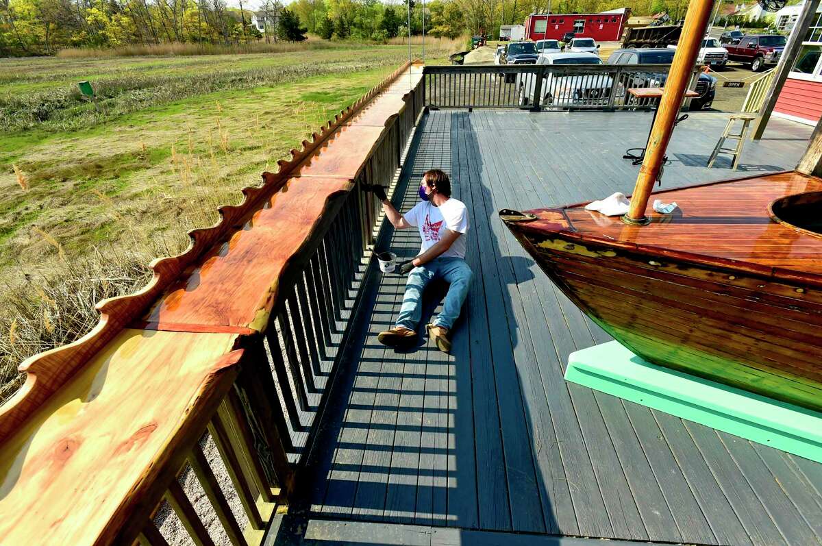 Branford, Connecticut - Friday, May 15, 2020: Brendan Conlin, son of owner Christopher Conlin of Lenny's Indian Head Inn, paints the back deck next to Sybil Marsh at the classic New England seafood restaurant. The Conlin's and the staff will be getting ables ready on their back deck and patio area, and in their parking lot as Connecticut restaurants prepare for a staged May 20th opening due to the Coronavirus / Covid-19 pandemic.